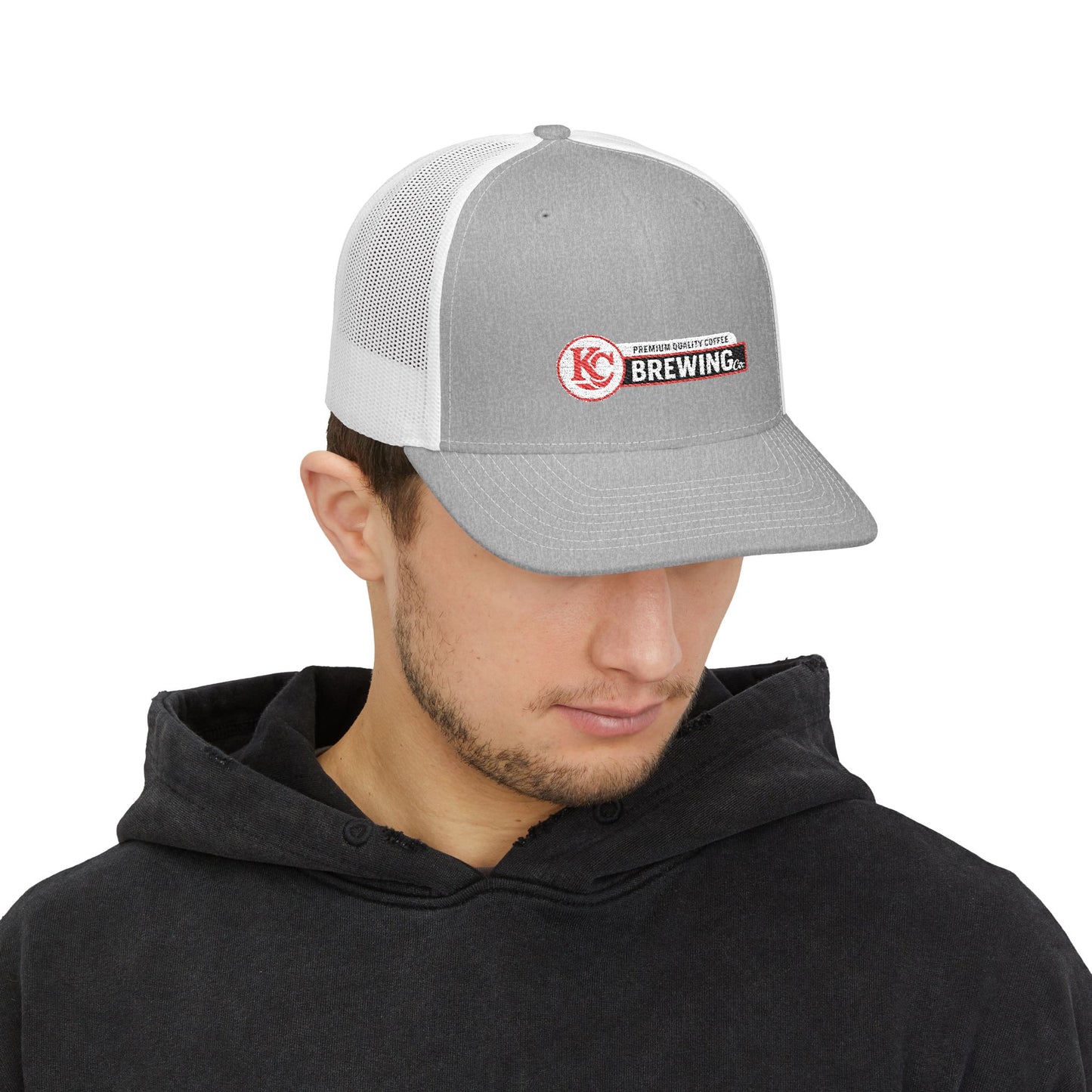 Person wearing a gray and white cap with a logo on a white background