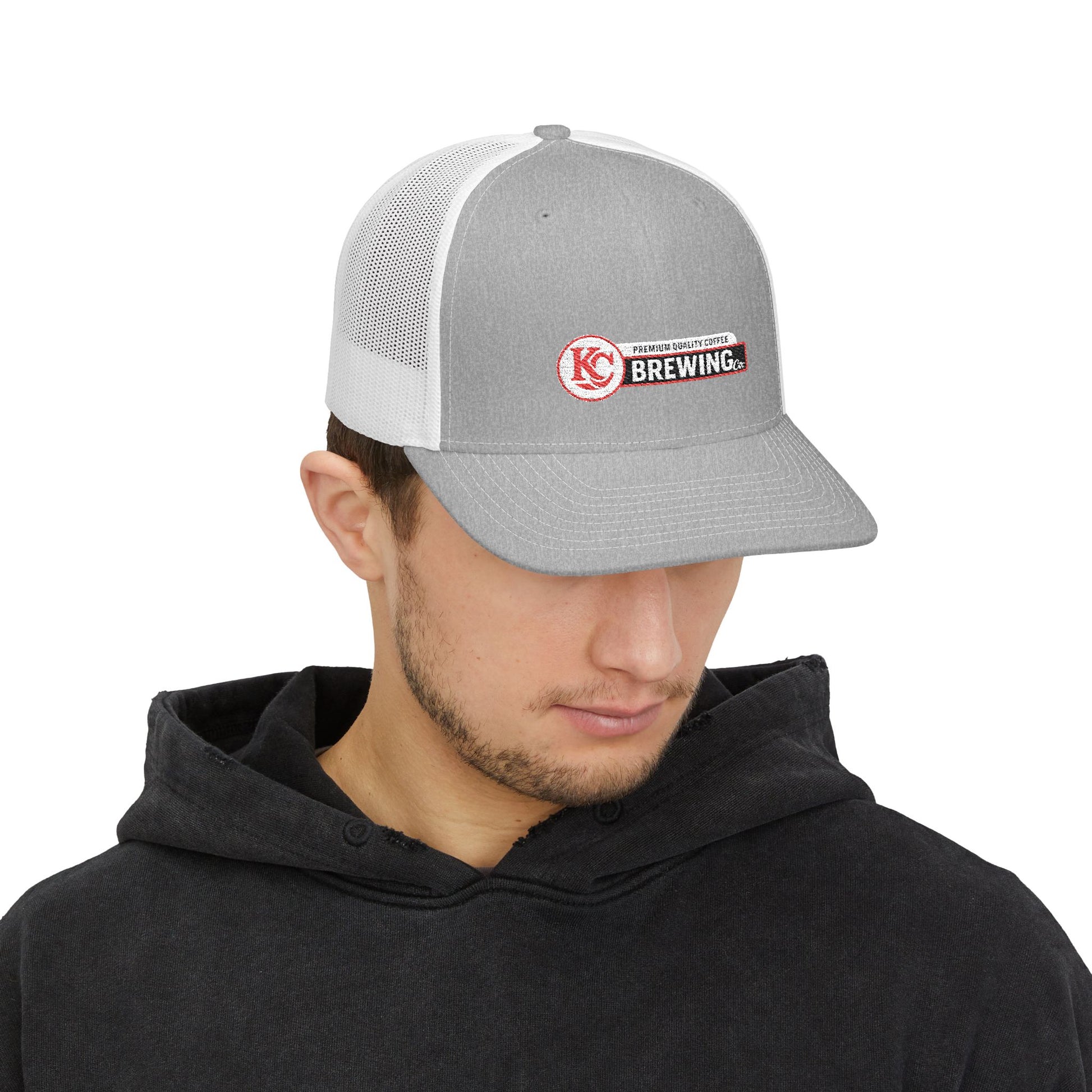 Person wearing a gray and white cap with a logo on a white background
