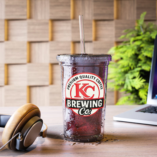 KC Brewing Co iced coffee in clear plastic cup with straw on wooden desk with headphones and laptop