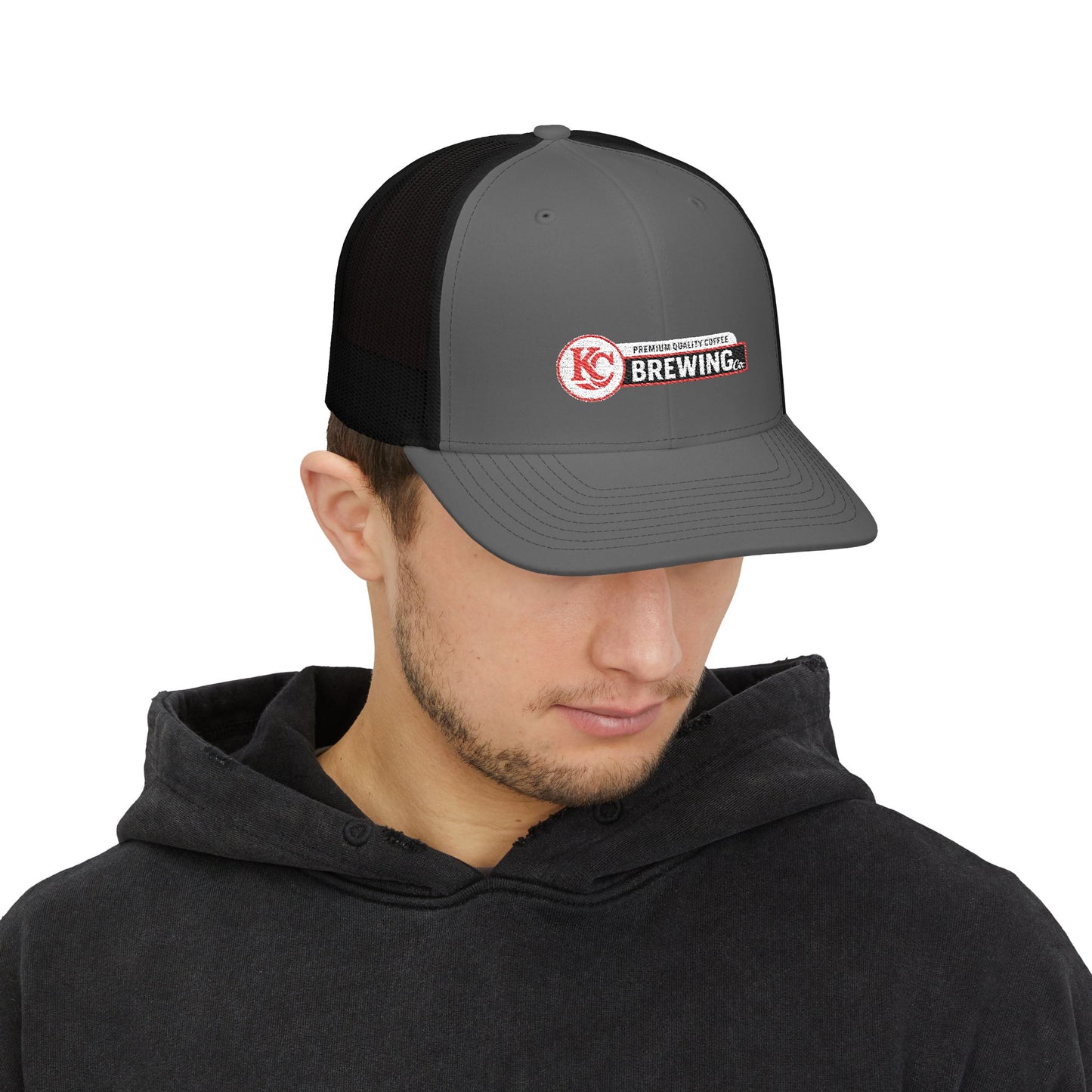 Man wearing a gray and black cap with a logo on a white background