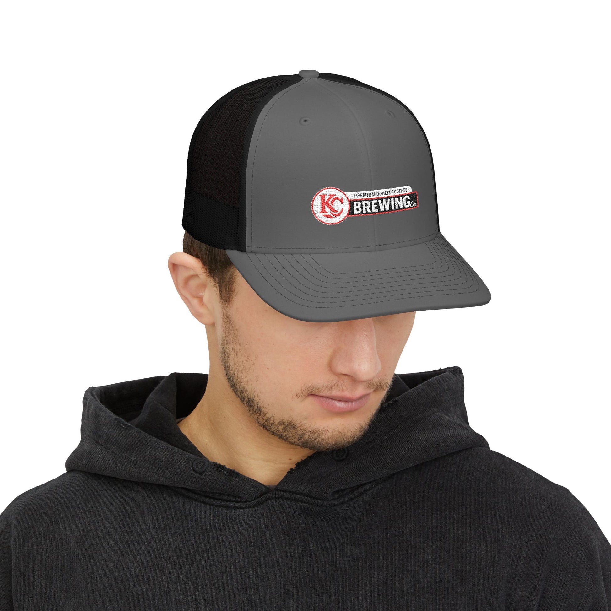 Man wearing a gray and black cap with a logo on a white background
