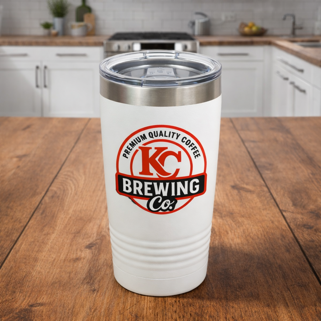 White KC Brewing Co insulated coffee tumbler with clear lid on wooden kitchen countertop