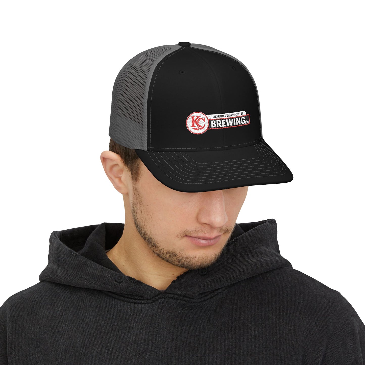 Person wearing a black and gray cap with a logo on a white background