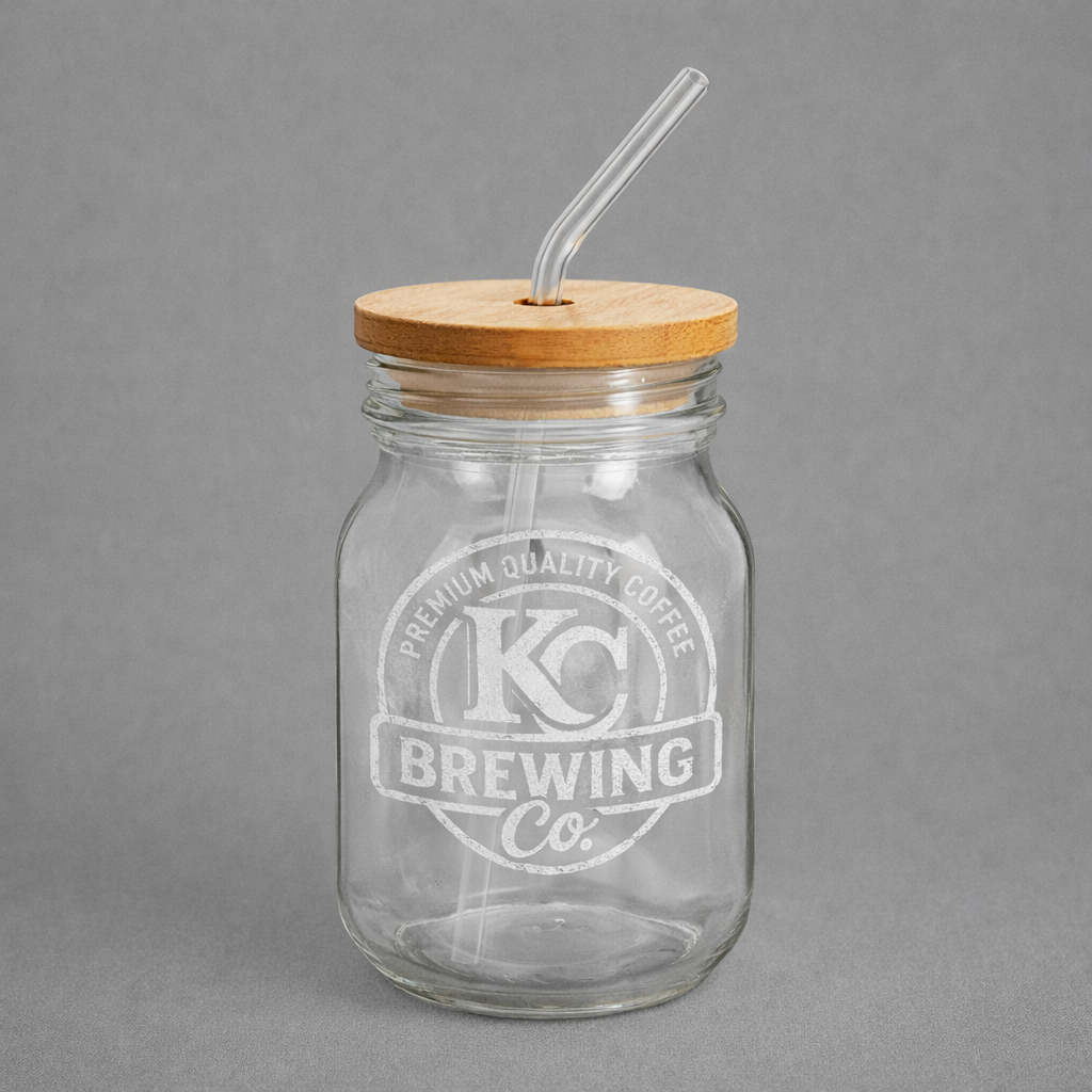 Clear KC Brewing Co glass jar with wooden lid and glass straw on gray background